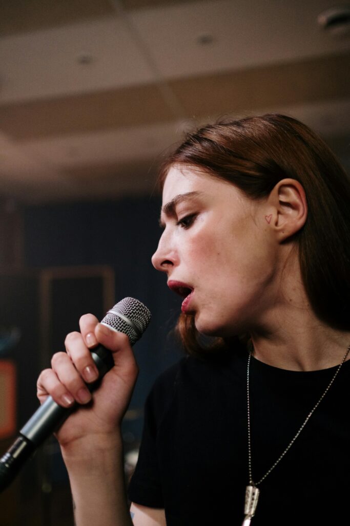 A passionate female vocalist performing with a microphone during a rehearsal indoors.